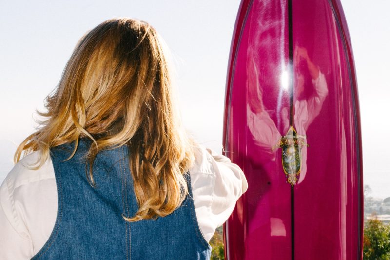 Guest with a pink surfboard looking out over the coast at a Laguna Sunset Sessions event