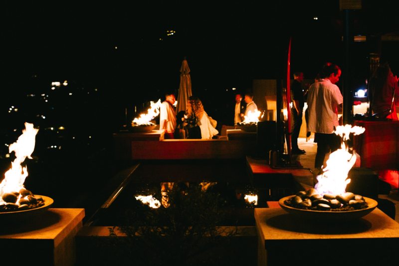 Fire bowls glowing on the terrace at night with guests gathered