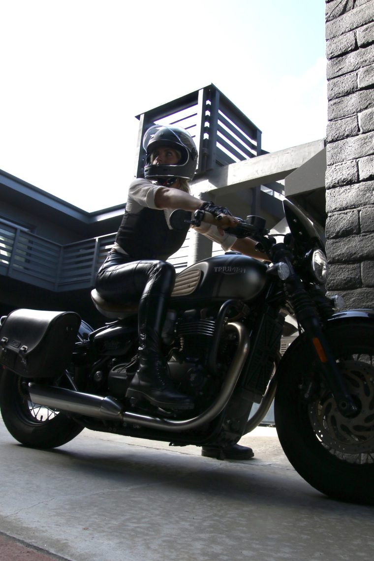 Aly on a cafe racer motorcycle against brick, Laguna