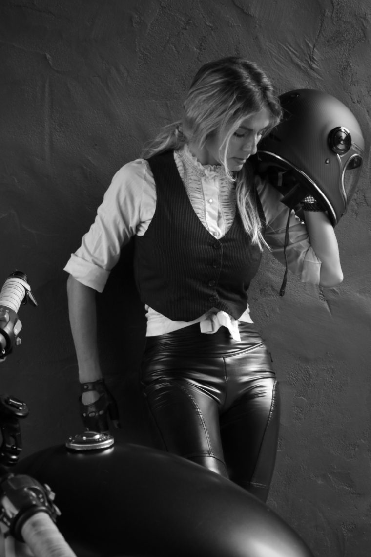 Aly holding a helmet against a concrete wall