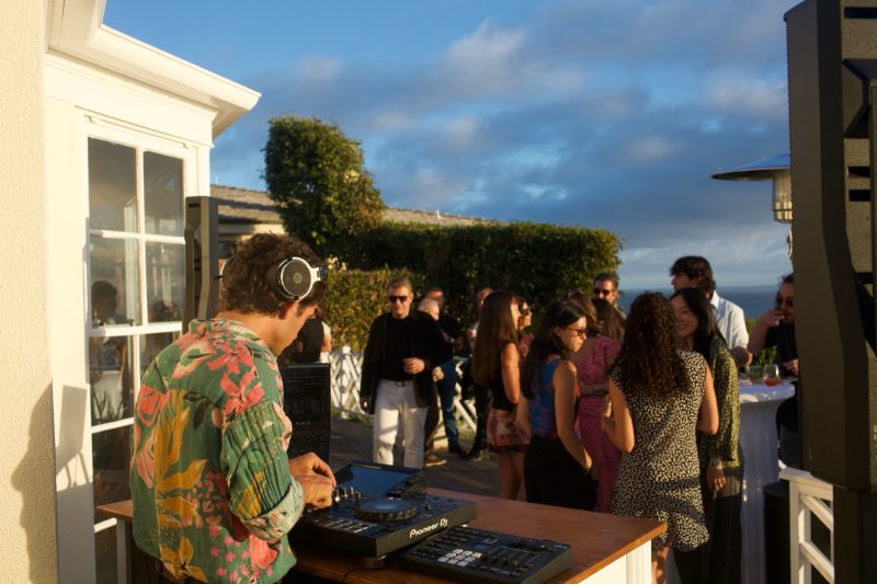 Scott Welch DJing a coastal sunset party with an ocean view
